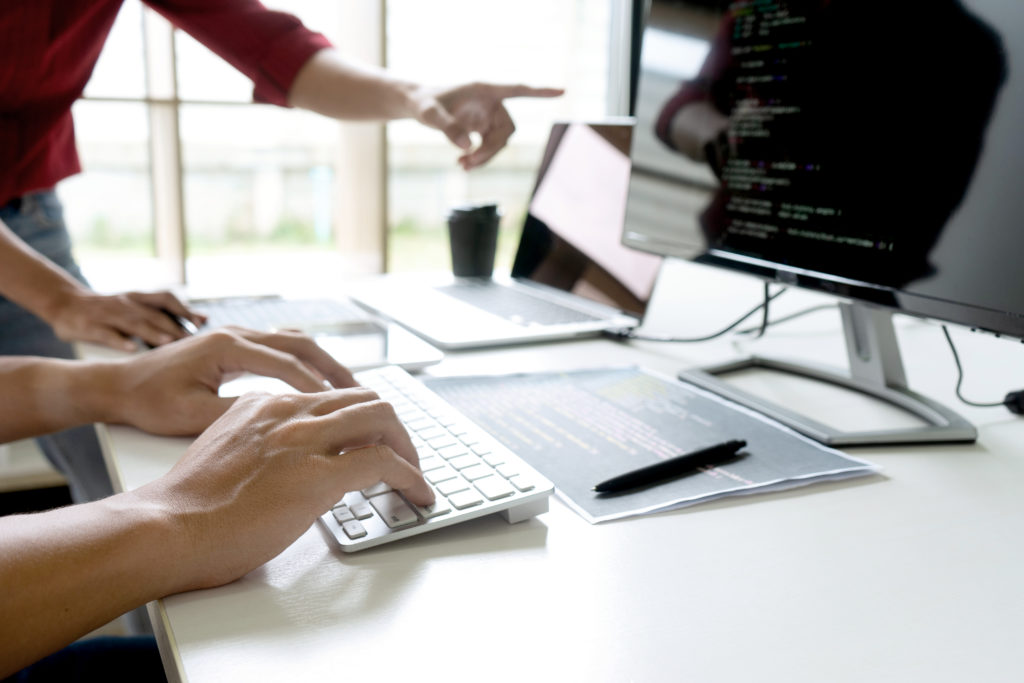 Teamwork team programmer working with computer desktop and laptop and computer code in paper print