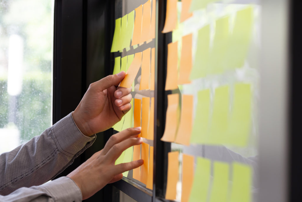 An IT employee attaches a note to the task board in the office